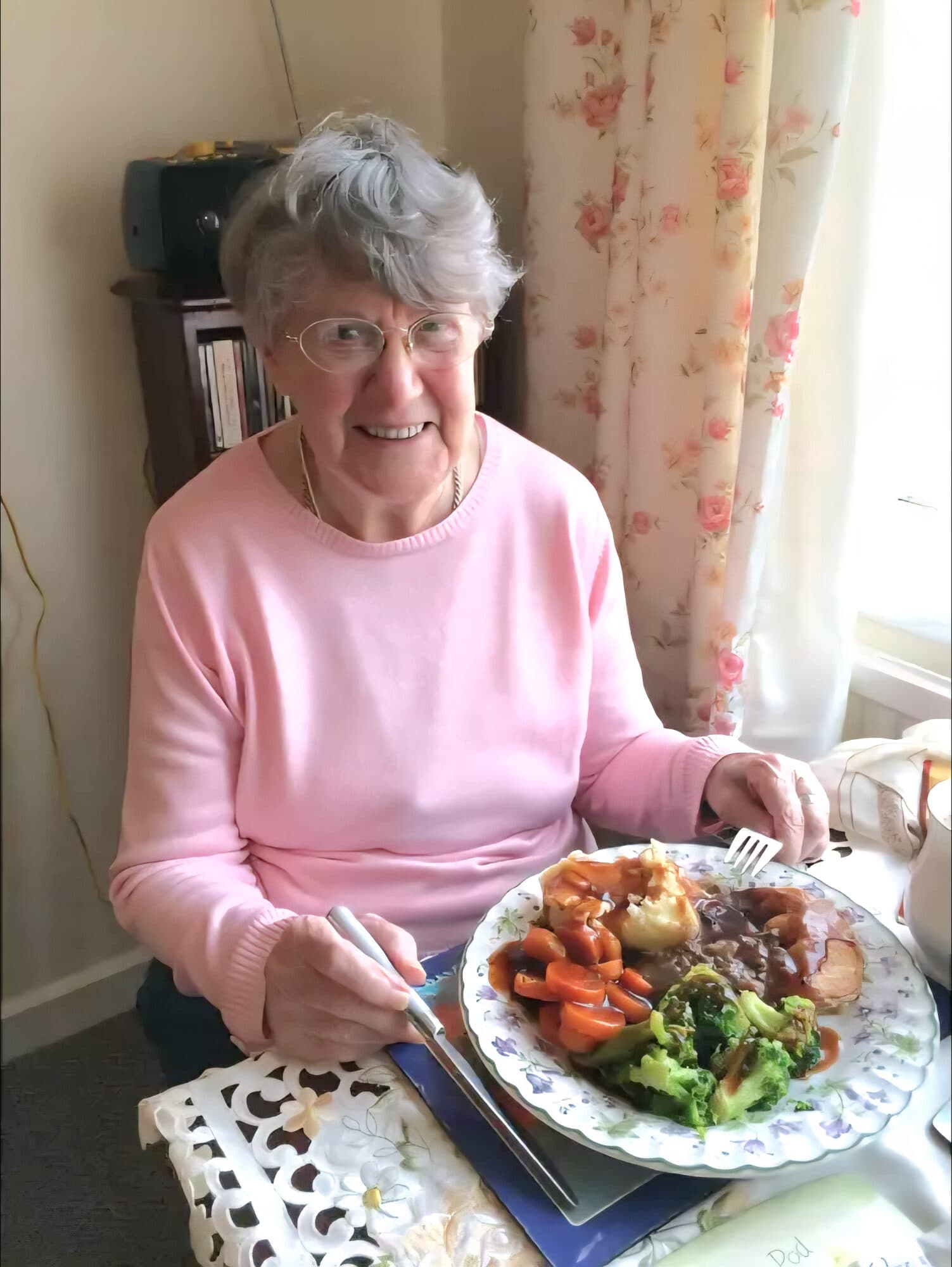 A client smiling over a freshly cooked roast dinner at home