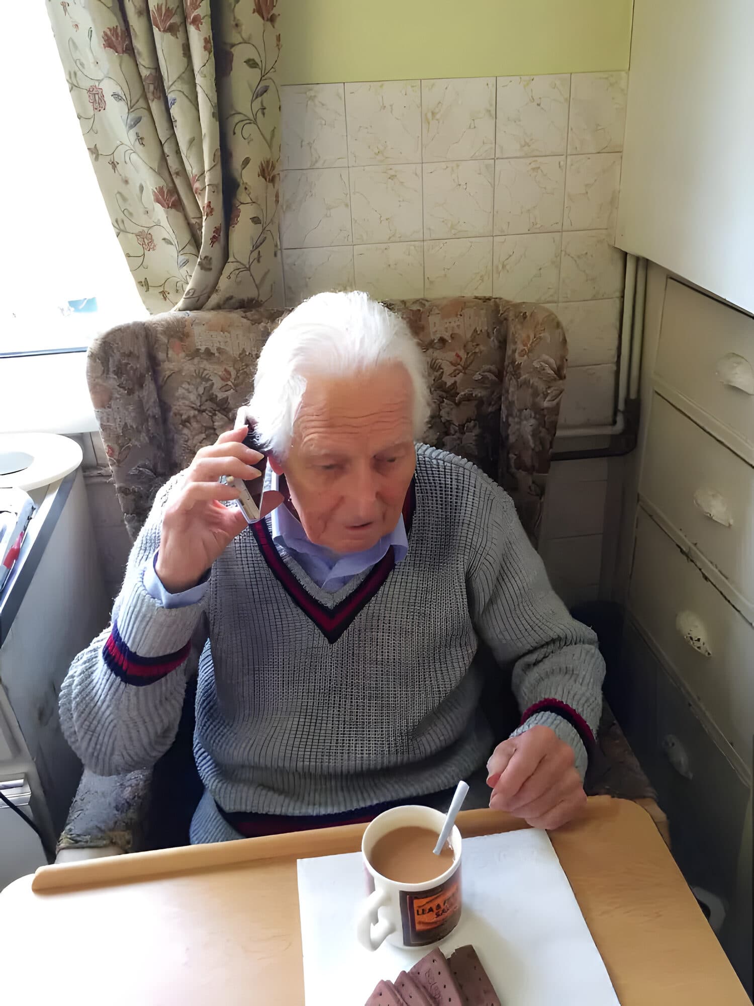 A client at home taking a phone call over a cup of tea